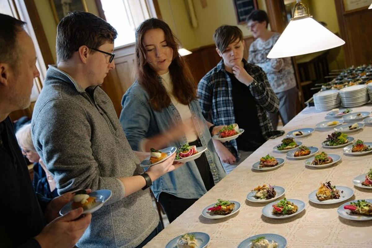 grupp inimesi, kes seisavad laua ümber toidutaldrikutega