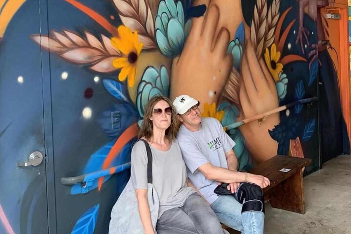a man and a woman sitting on a bench in front of a mural