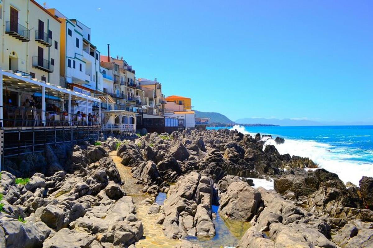 una spiaggia con rocce, edifici e l'oceano