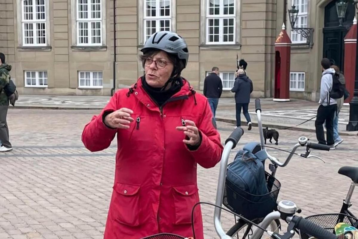 Kona í rauðum frakka stendur við hliðina á hjóli