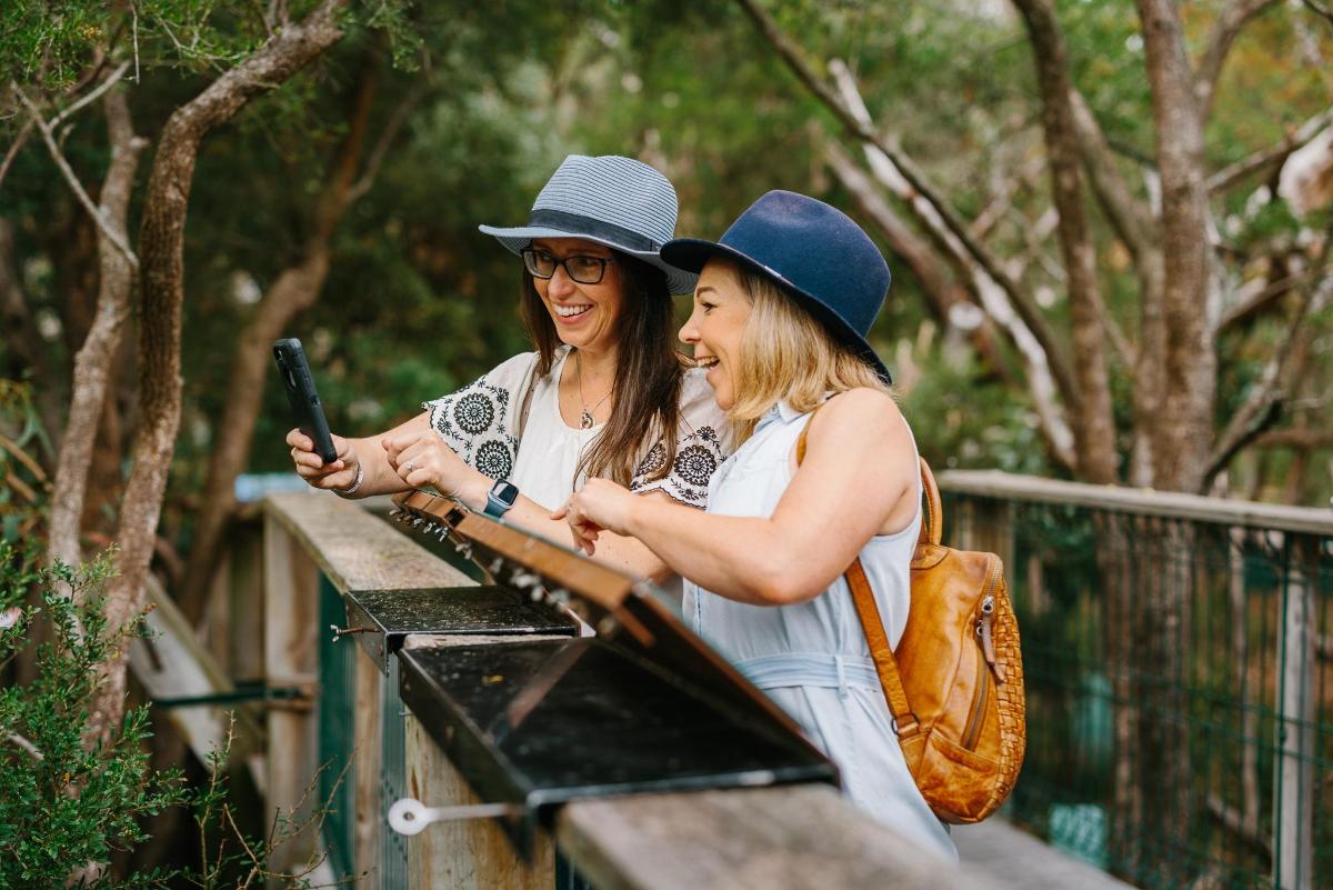 two women are laughing while looking at a cell phone