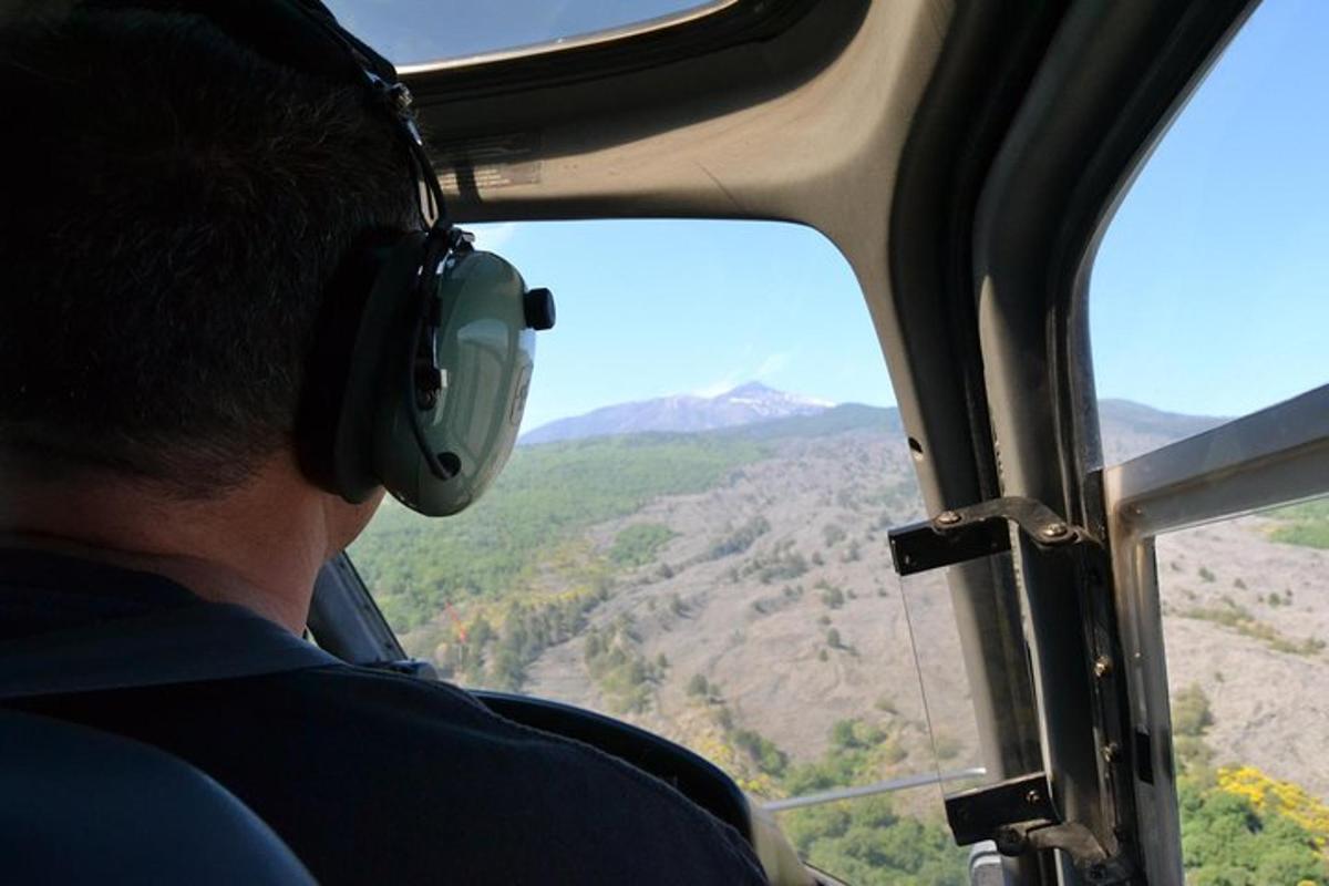 moški s slušalkami gleda skozi okno helikopterja