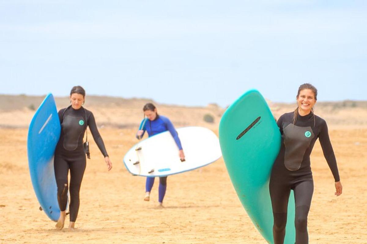 three surfers walking on the beach with their surfboards