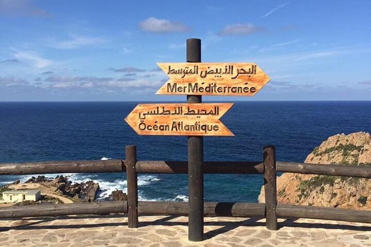 un cartello con frecce sulla spiaggia con l'oceano