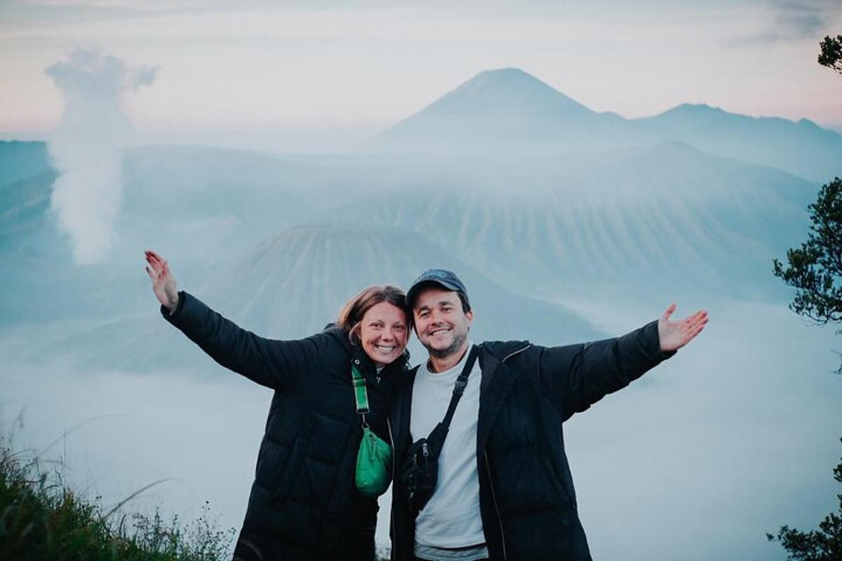 a man and woman pose for a picture in front of a mountain