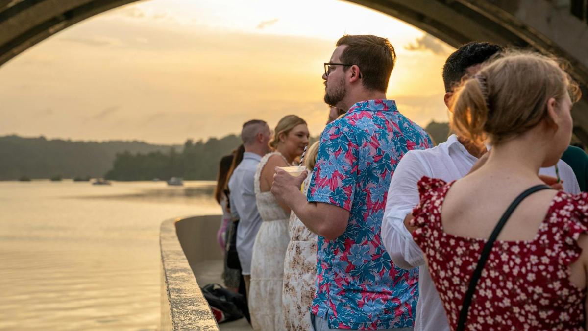 a group of people standing on a bridge near the water
