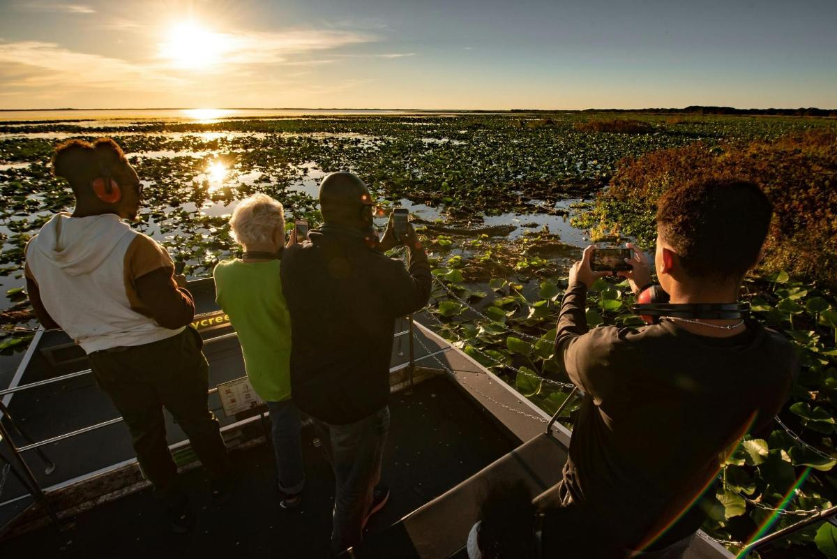 a group of people taking pictures of the sunset