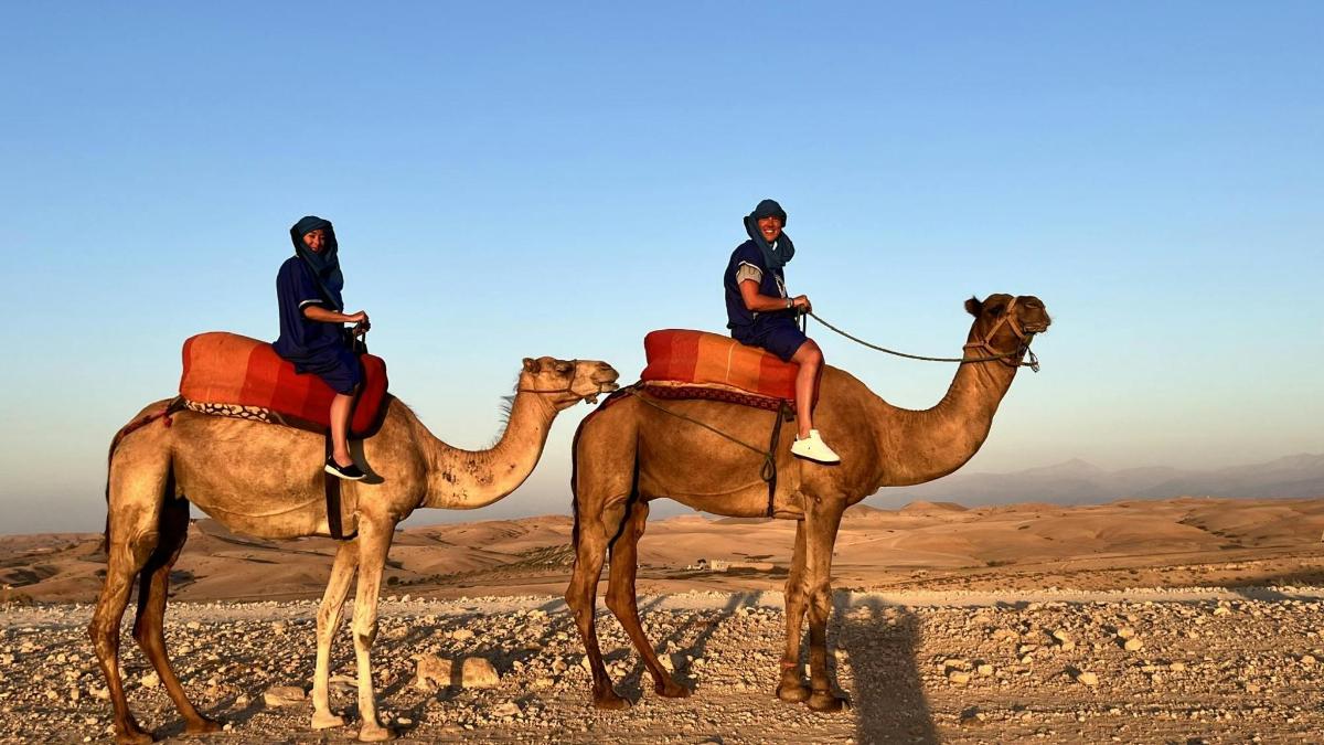 zwei Männer reiten auf dem Rücken von Kamelen in der Wüste