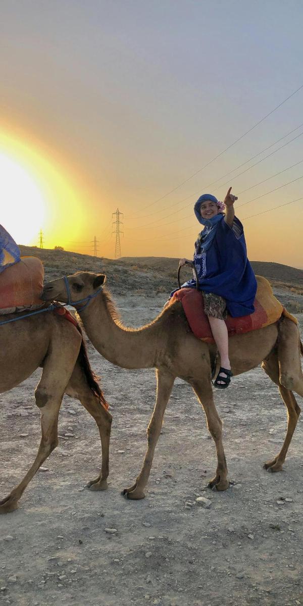 eine Person, die auf einem Kamel in der Wüste reitet