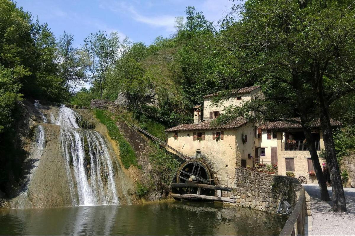 Una cascada junto a un edificio y una rueda hidráulica.