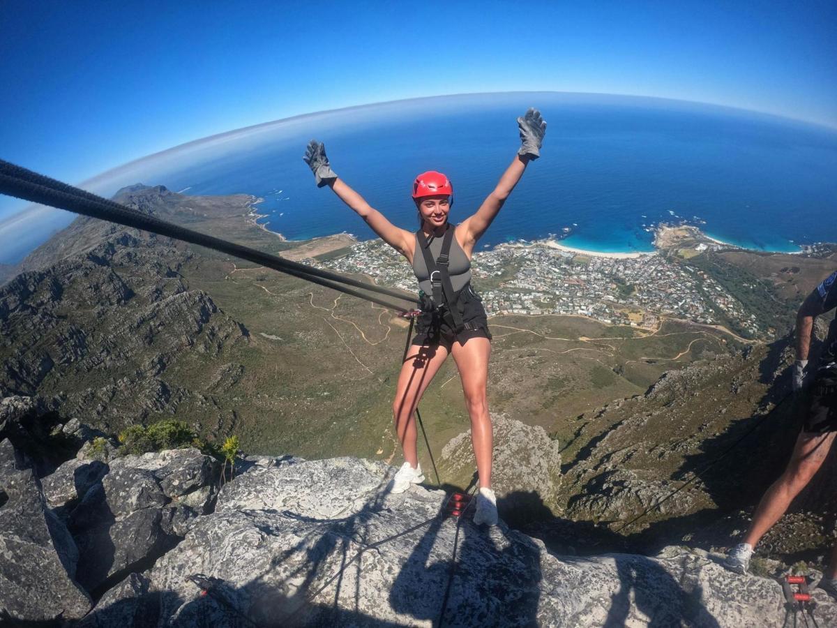 una donna in piedi sulla cima di una montagna con le braccia alzate