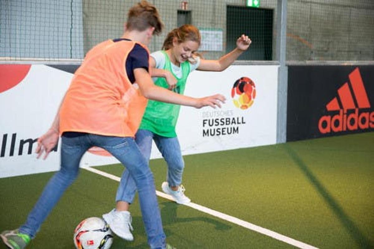 a man and a girl playing with a soccer ball