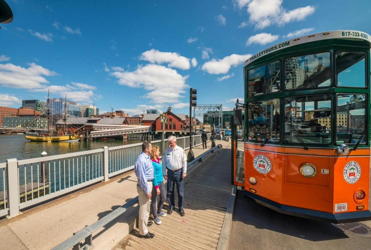 en gruppe mennesker som står ved siden av en buss på en bro