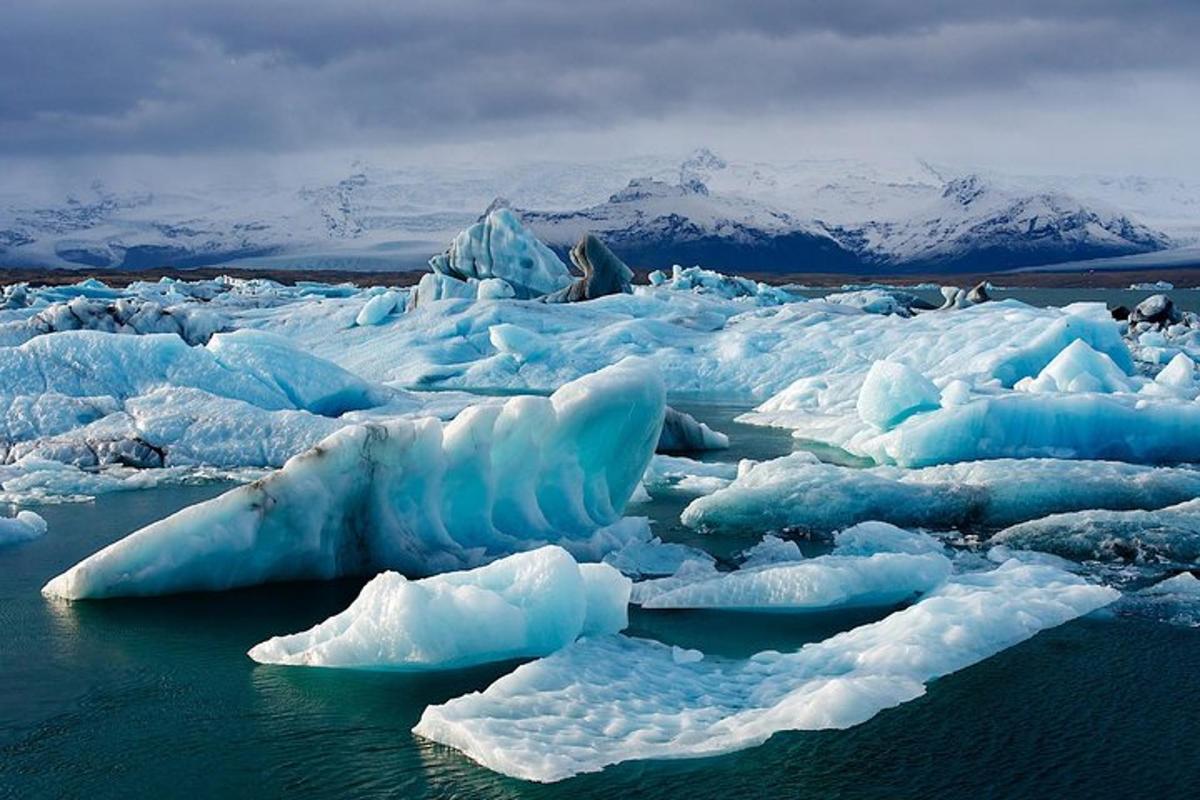 a group of icebergs in the water with mountains