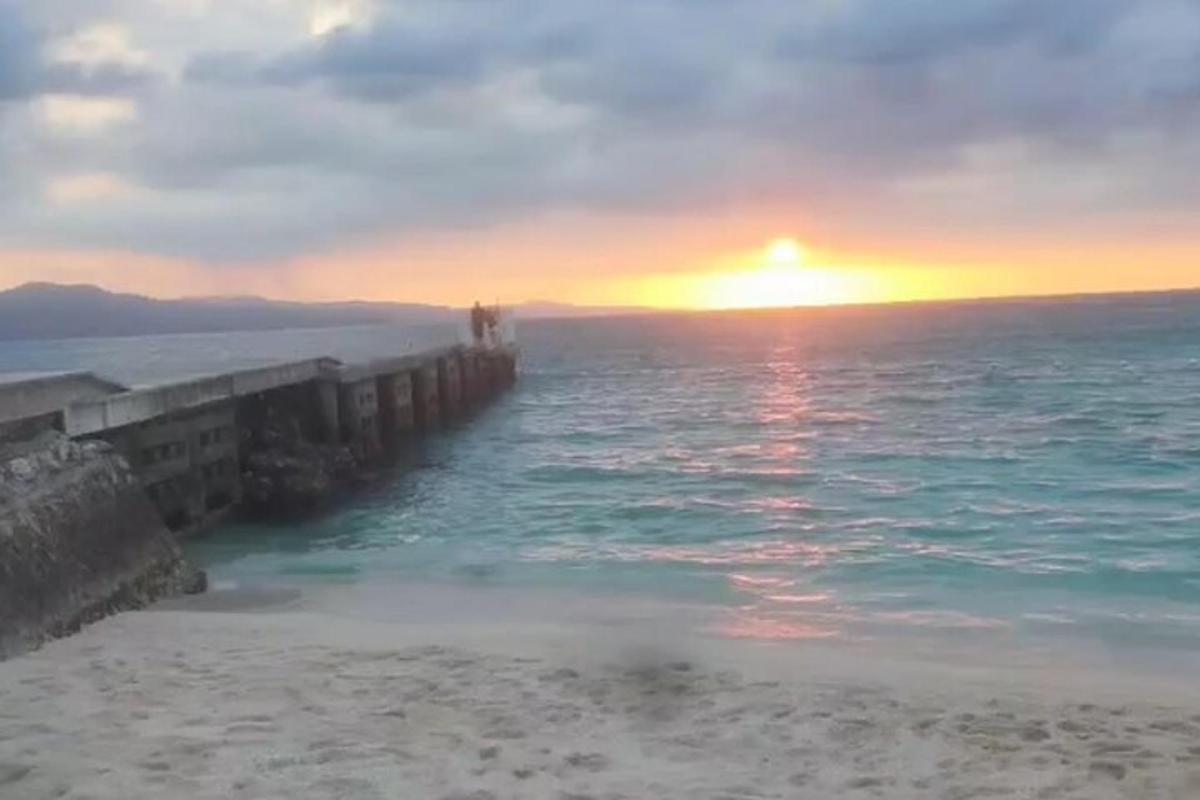 una posta de sol sobre l'oceà amb un moll