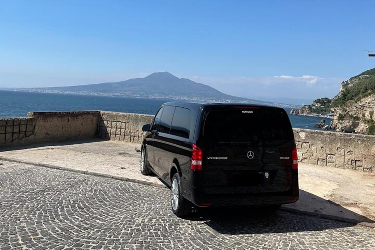 un furgone nero parcheggiato su una strada lastricata di mattoni vicino all'oceano