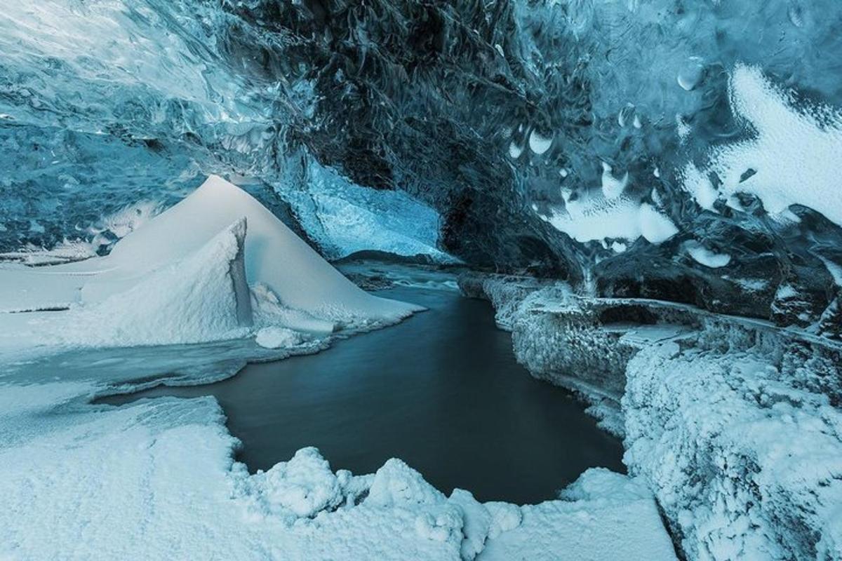 una grotta di ghiaccio con uno specchio d'acqua e neve