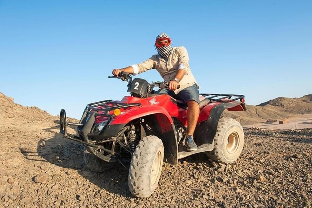 muž sedící na čtyřkolce v poušti