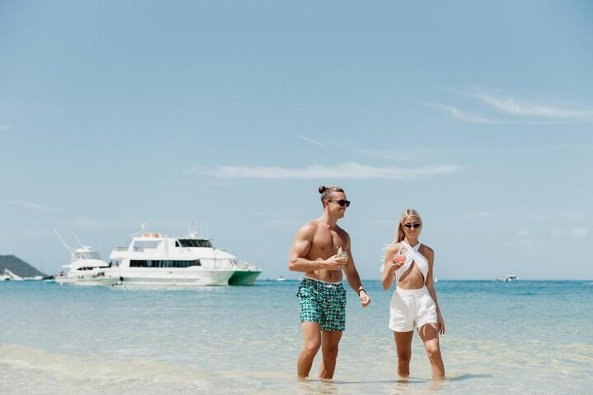 two people walking on the beach with a boat