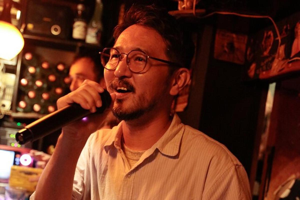 un uomo che canta in un microfono in un bar