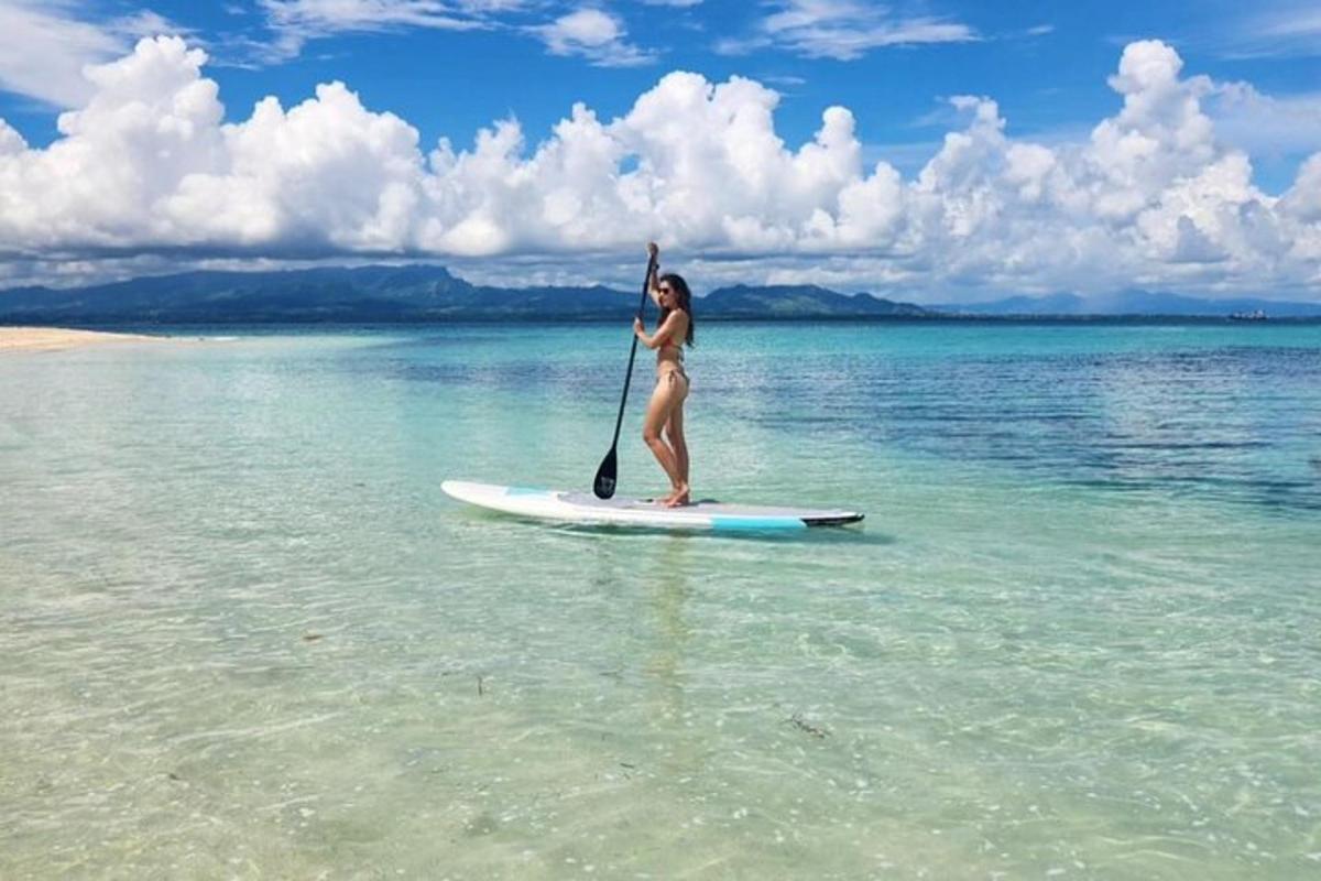 a woman in a bikini standing on a paddle board in the water