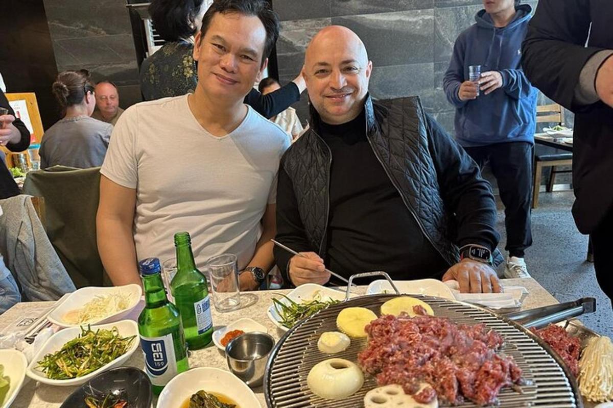 two men sitting at a table with food