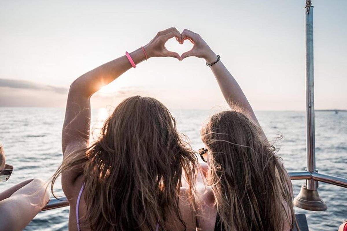 Dos mujeres haciendo un signo de corazón en un barco