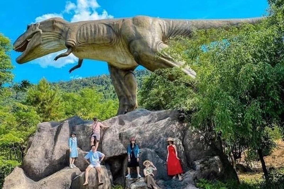 skupina lidí stojících před sochou dinosaura