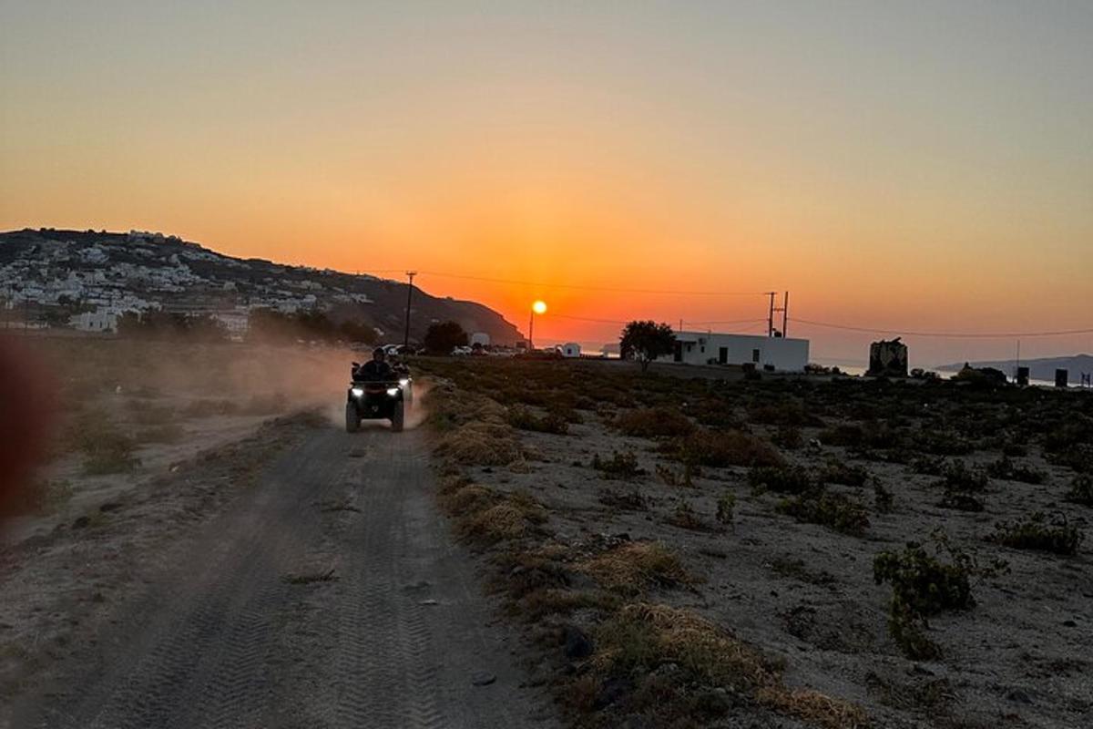 Una persona que conduce una motocicleta por un camino de tierra al atardecer.