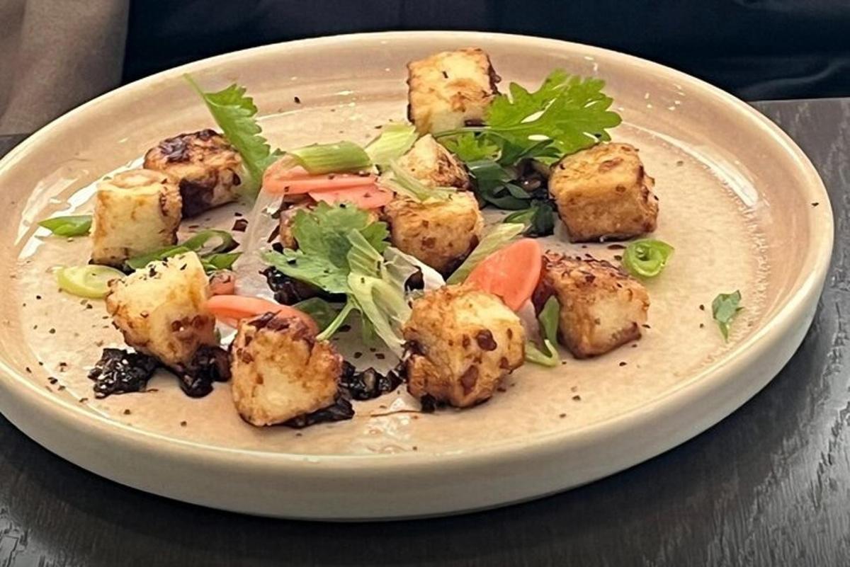 um prato de comida com tofu e vegetais em uma mesa