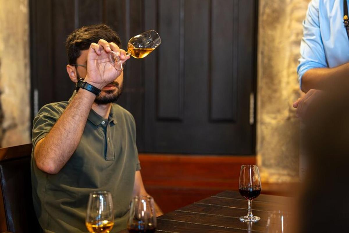 čovjek sjedi za stolom i pije čašu vina
