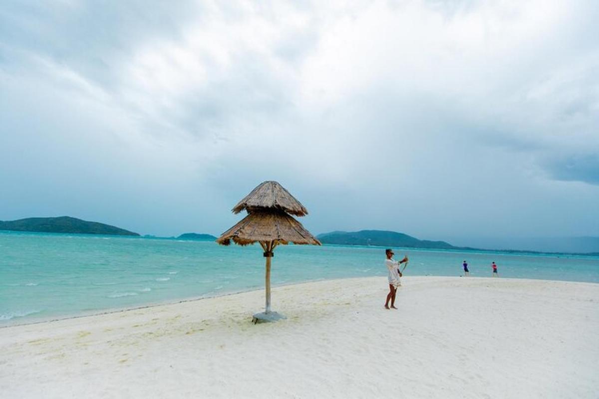 một người đàn ông đứng trên bãi biển bên cạnh một chiếc ô