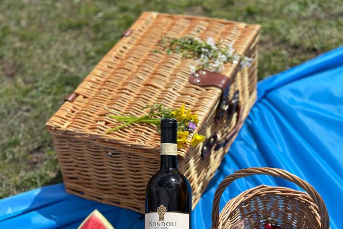 isang bote ng alak na nakaupo sa tabi ng isang picnic basket