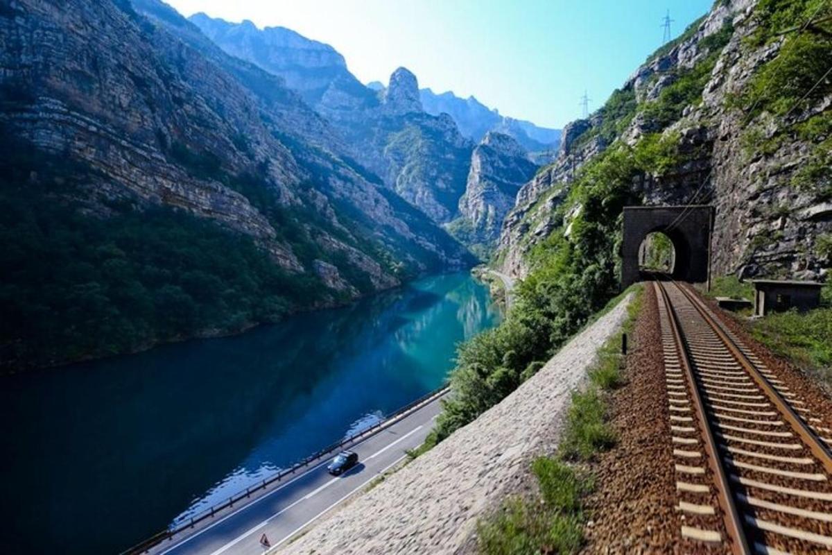 uma linha de trem próxima a um rio com um túnel