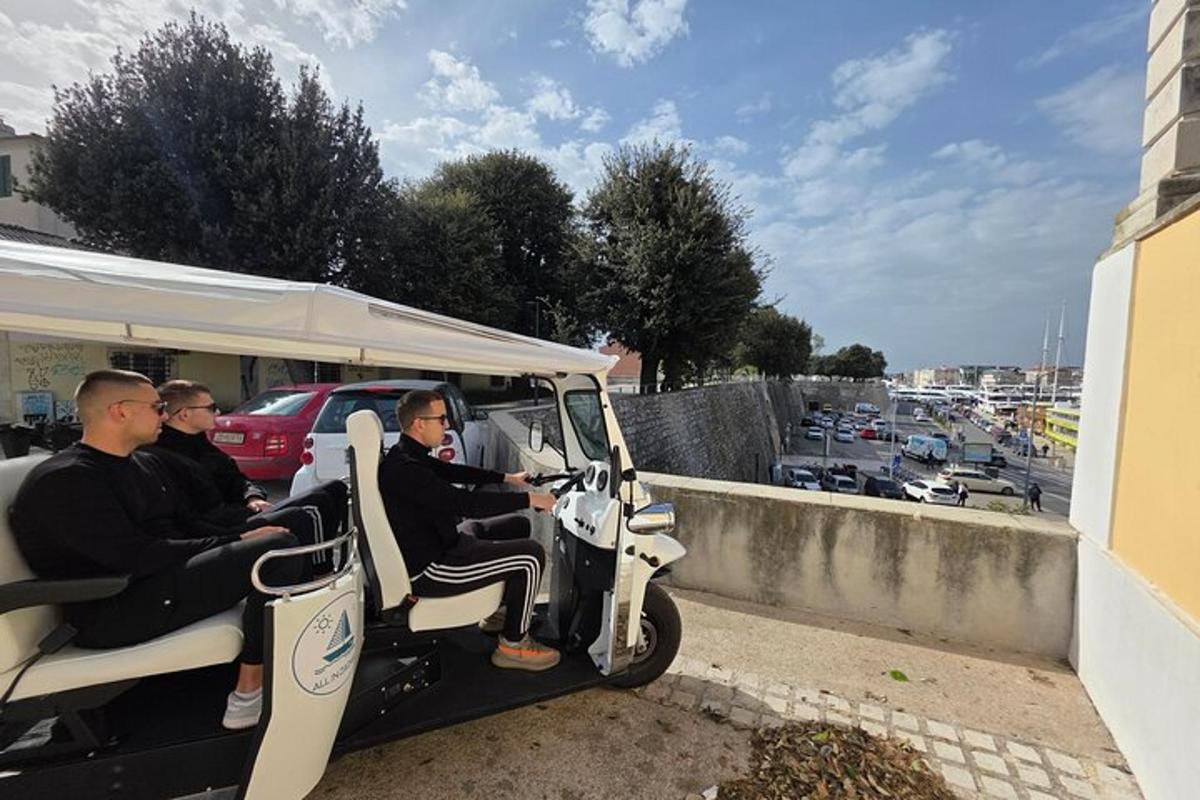 skupina mužů jedoucích v golfovém vozíku