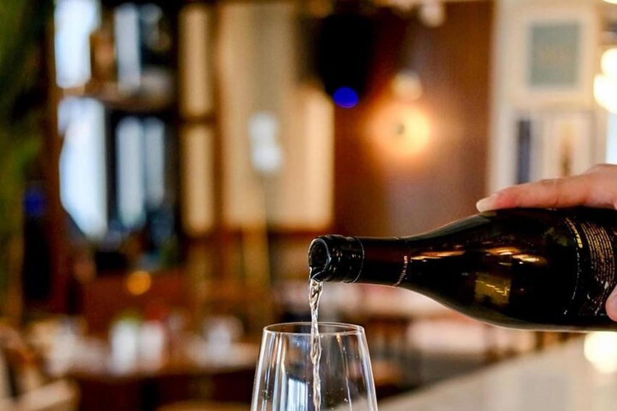 una persona che versa il vino in un bicchiere da vino