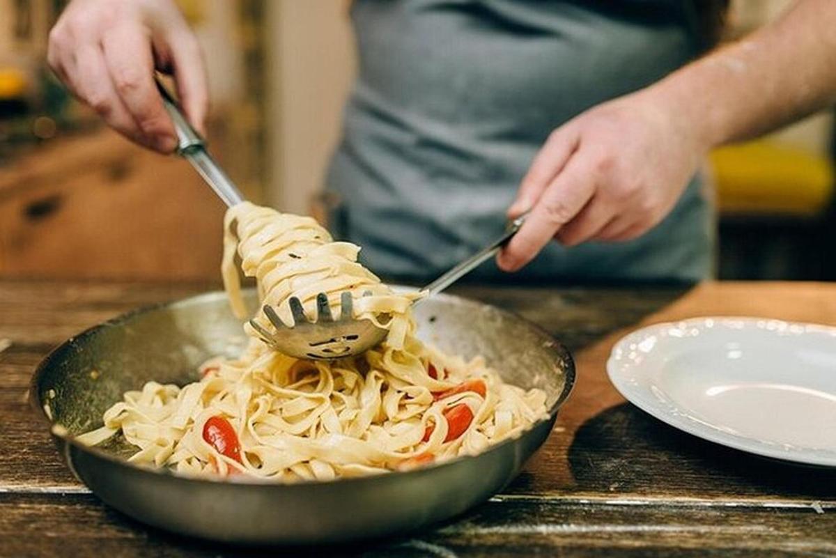 Una persona está comiendo pasta con tenedor y cuchillo.