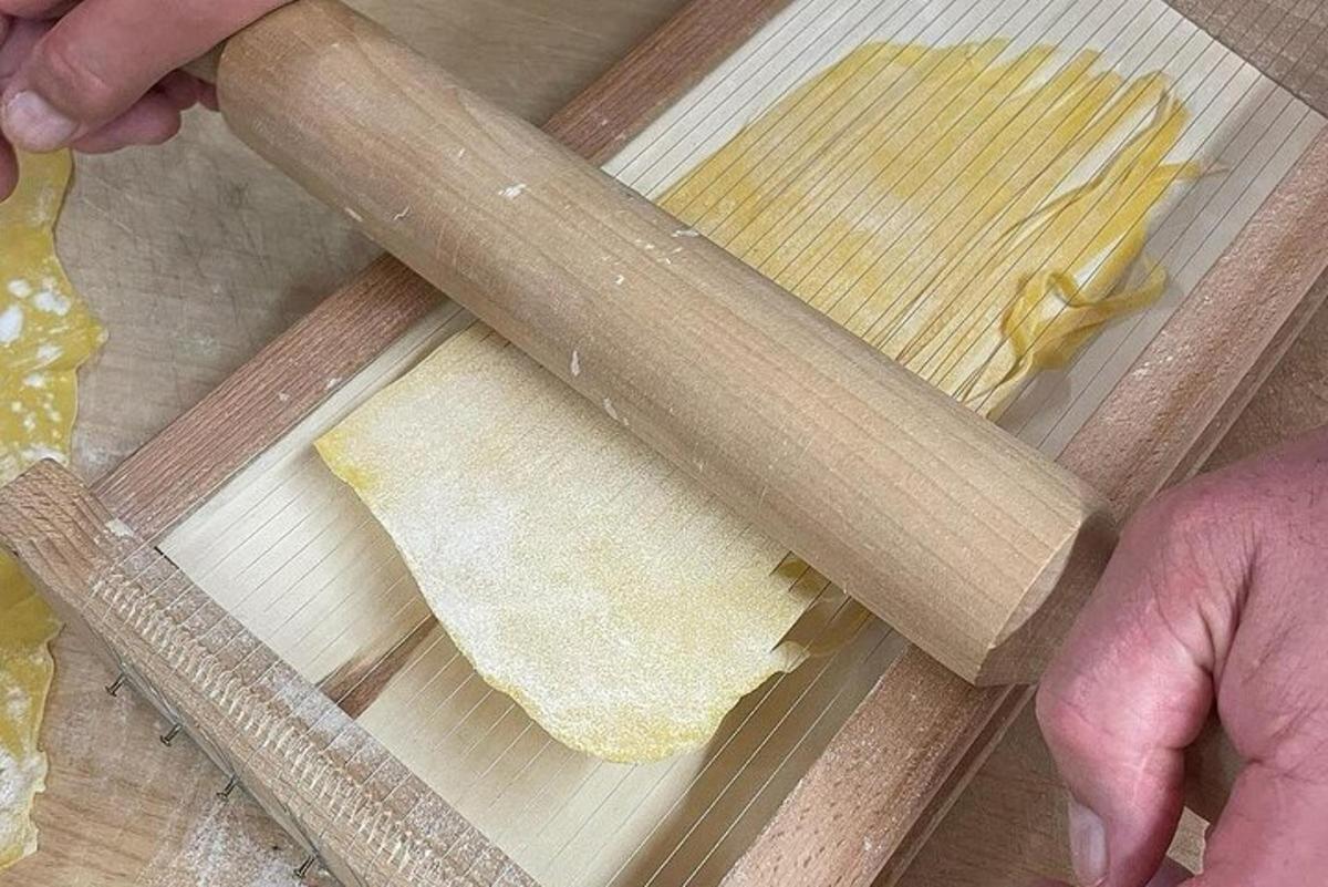 Una persona está haciendo pasta en una tabla de cortar con un cuchillo.