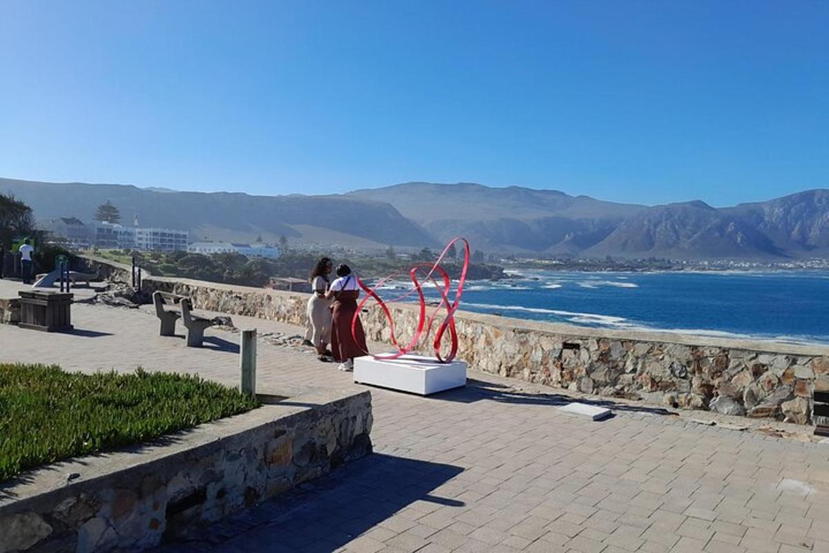 duas pessoas em pé ao lado de uma escultura na praia