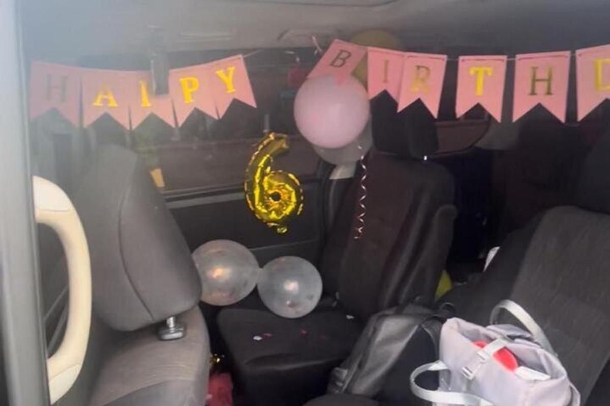 ein Rücksitz eines Autos mit Luftballons und einem Happy Birthday-Banner