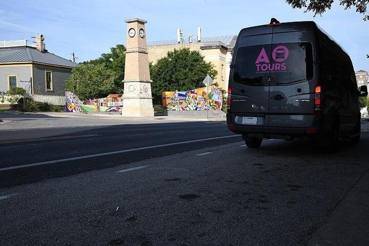 a black van driving down a street with a clock tower