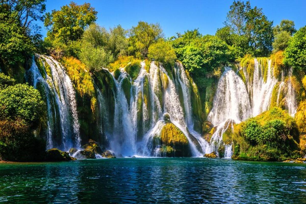 una cascata sopra un lago di fronte a una foresta