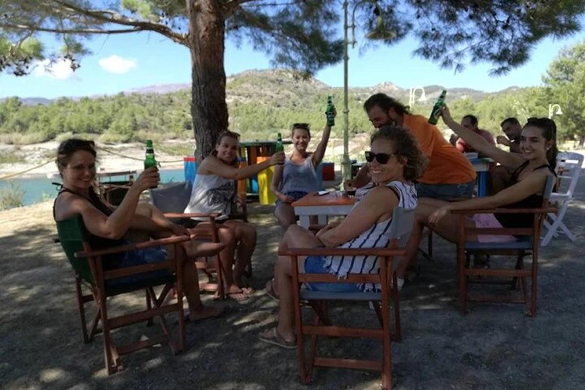 een groep mensen die aan een tafel zitten en bier drinken