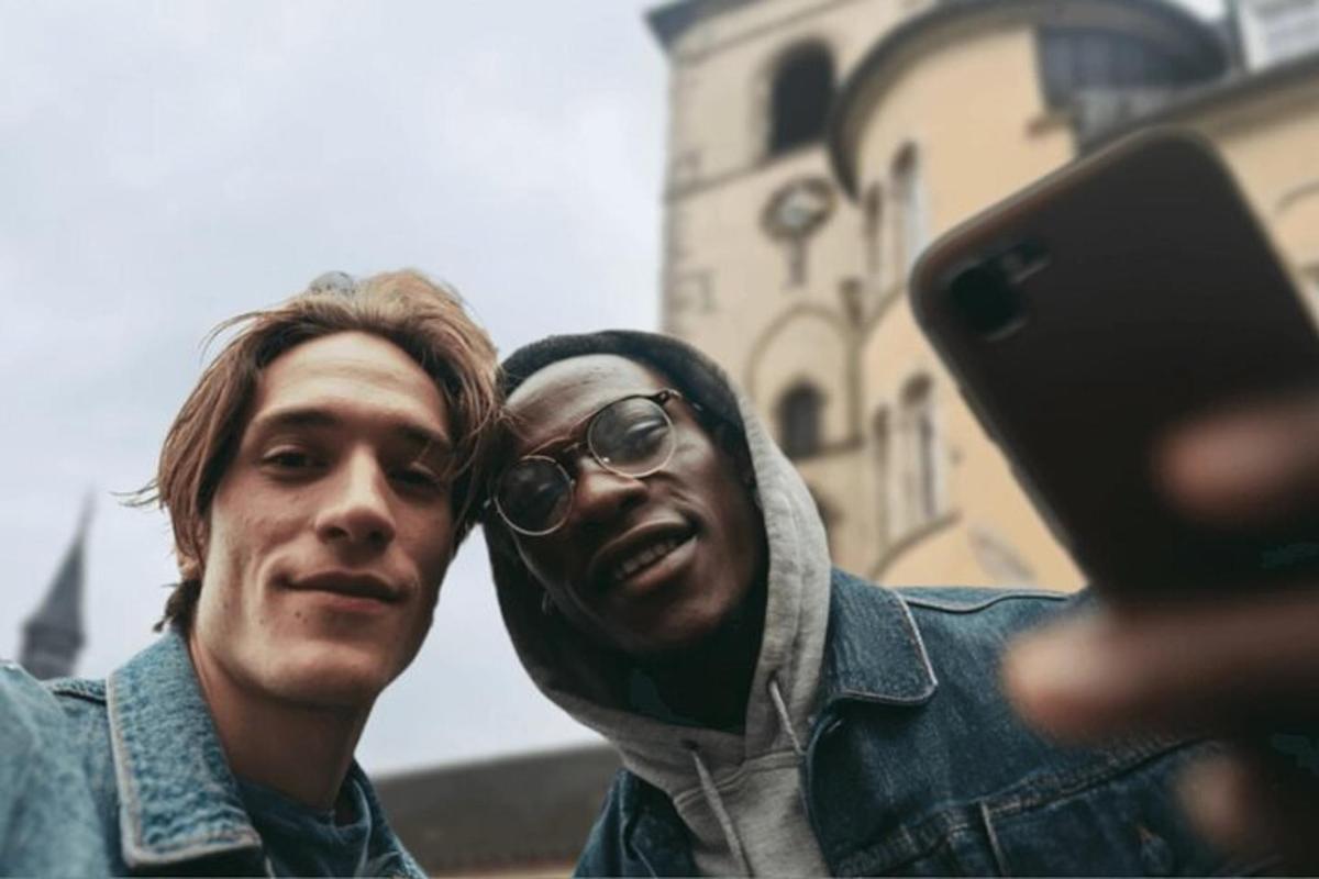 due uomini in piedi uno accanto all'altro che guardano un cellulare
