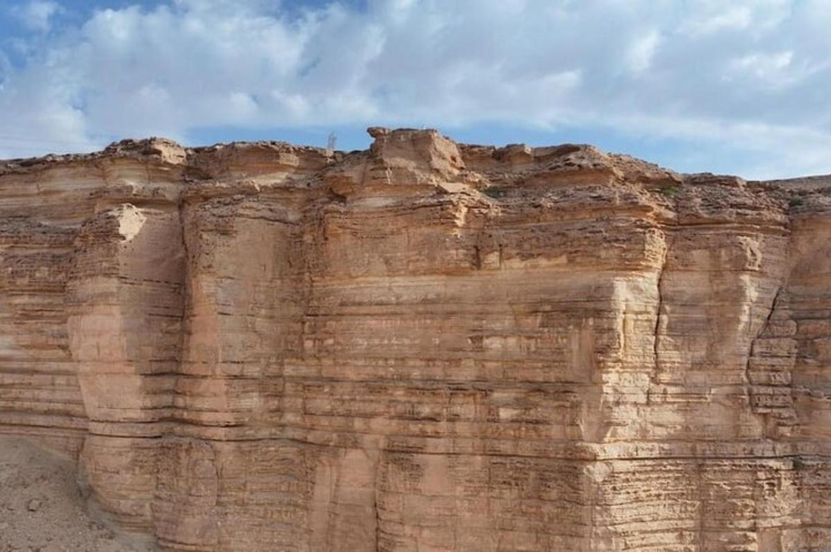 a rock formation in the desert against a cloudy sky