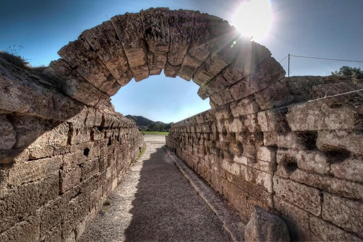 μια αψίδα σε έναν τοίχο από τούβλα με τον ήλιο στο φόντο