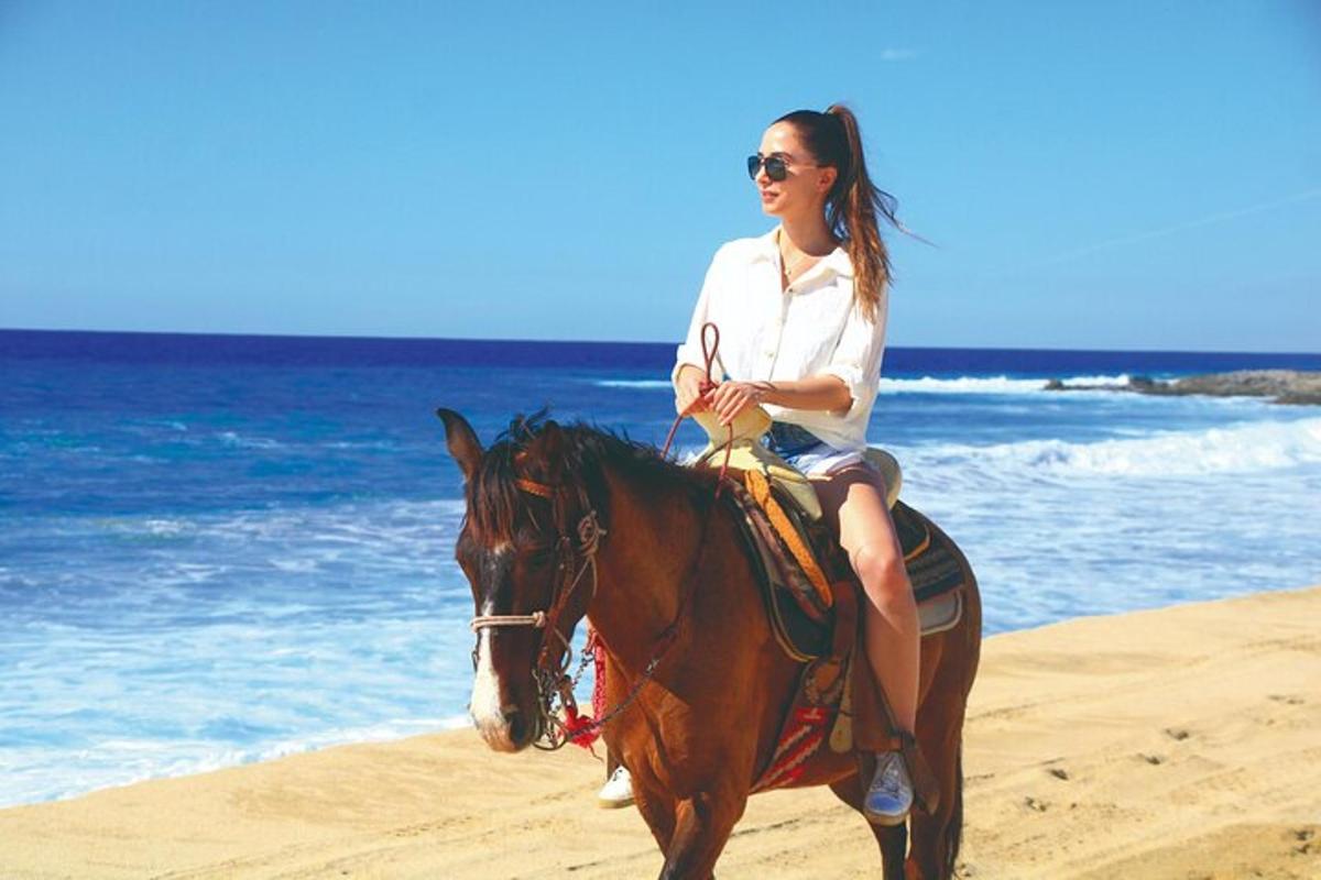 een vrouw die op een paard op het strand rijdt