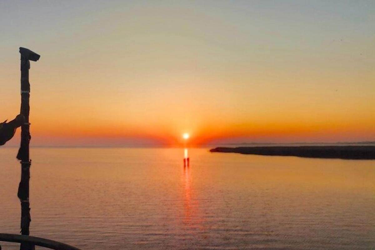 un tramonto sull'acqua con un palo in primo piano