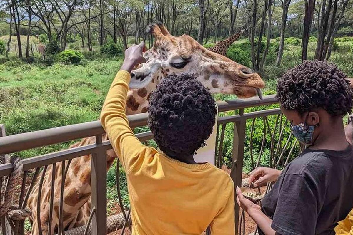 due bambini accarezzano una giraffa allo zoo