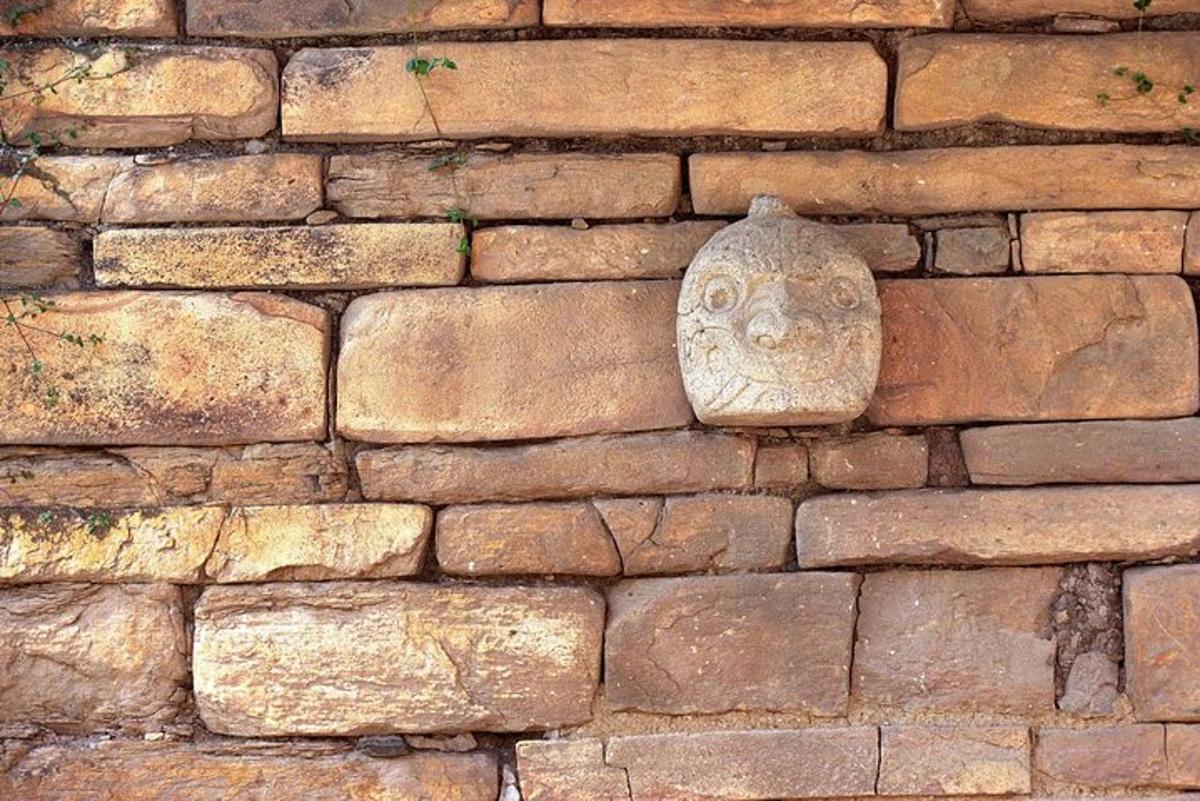 um rosto de pedra na lateral de uma parede de tijolos